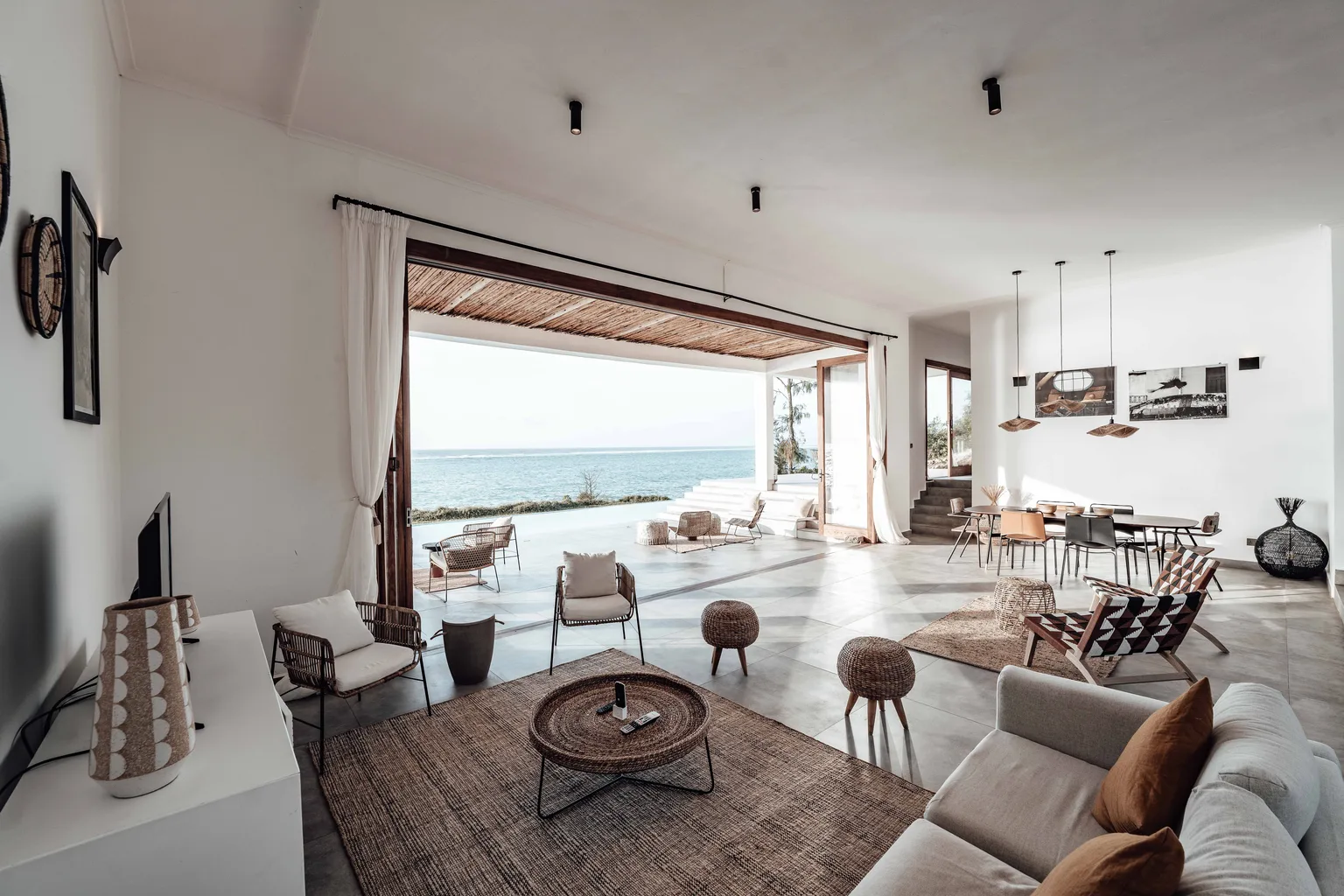 Open coastal living room with a large area rug and doors opening toward the ocean