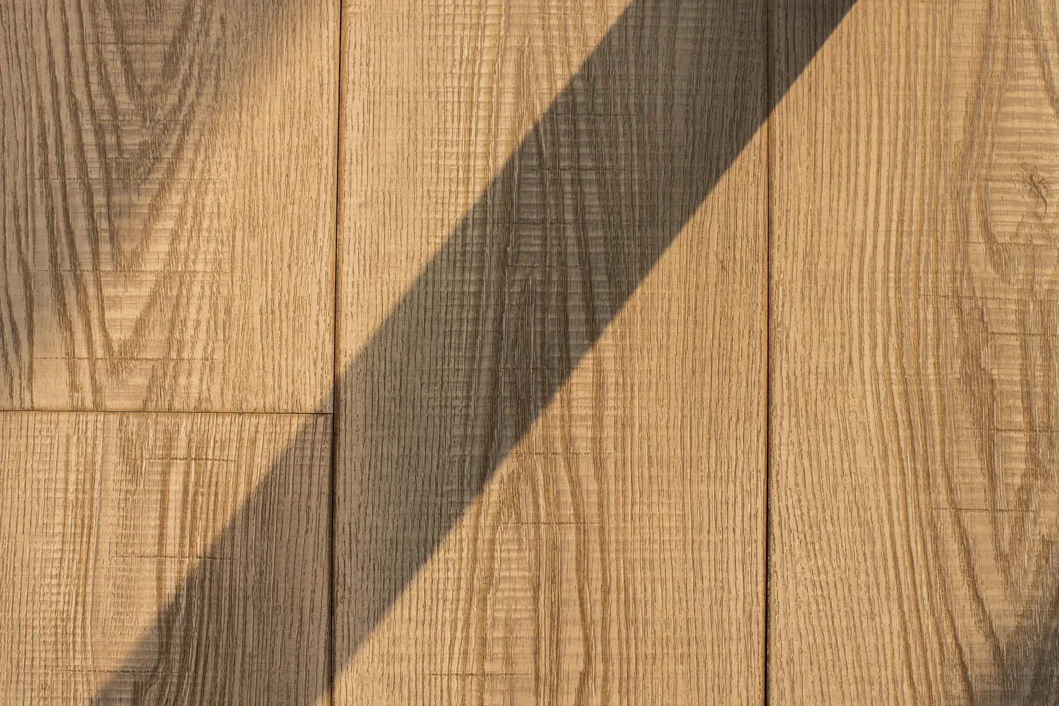 Close view of wooden floor planks with light and shadow across the grain