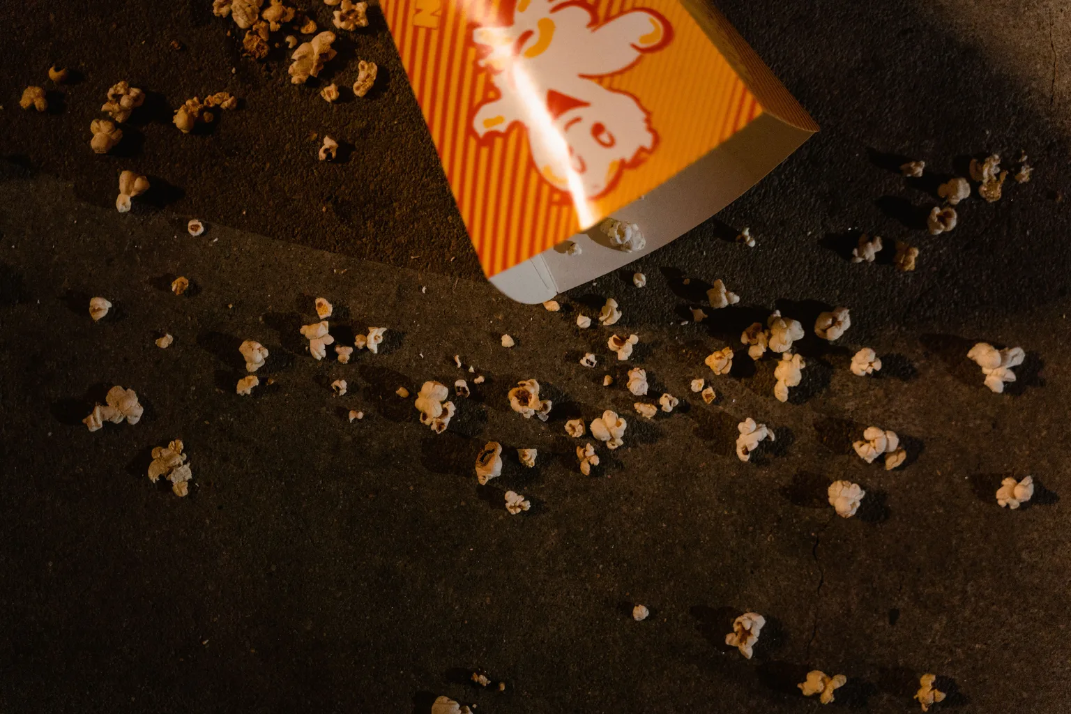 An overturned tub of popcorn scattered across a floor