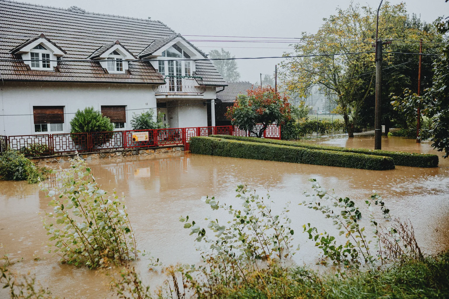 A suburban house surrounded by brown standing floodwater after heavy rain