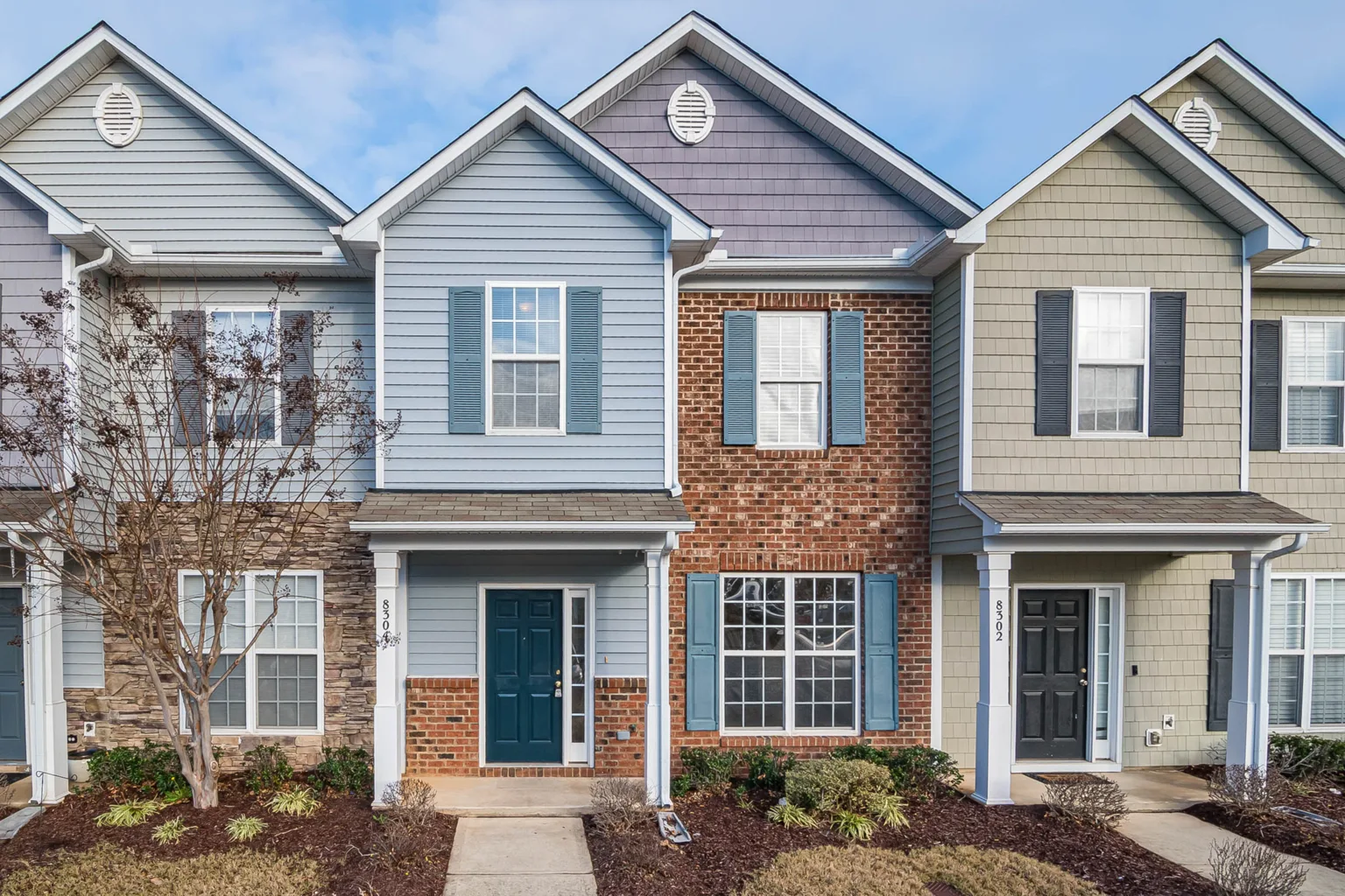 A row of two-story townhouses with brick and siding facades on a clear day